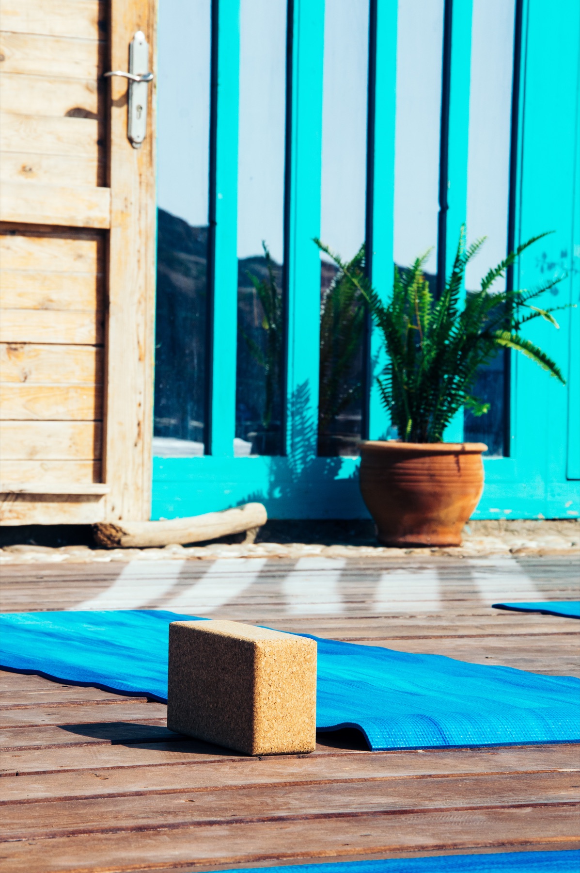 A yoga mat and block on a wooden deck, illustrative stock detail